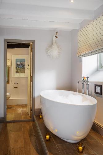 a bathroom with a large white tub in a room at The Hideaway at Tregoose Old Mill in Newquay