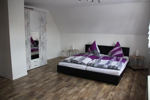 Schlafzimmer mit einem Bett mit lila Kissen und einem Spiegel in der Unterkunft Landhaus "Zum Frosch" in Kalbsrieth