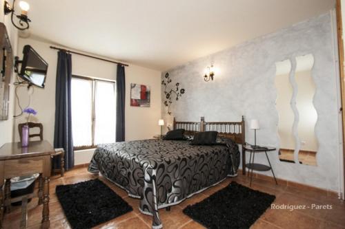 a bedroom with a bed and a table and a desk at El Pradón in Mar