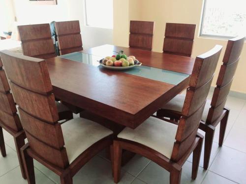 a wooden table with chairs and a bowl of fruit on it at Discoverequador in Tonsupa