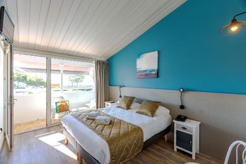 a bedroom with a bed with a blue wall at Hôtel Restaurant Le Grand Large - Face à la plage - Ile de Ré in Rivedoux-Plage