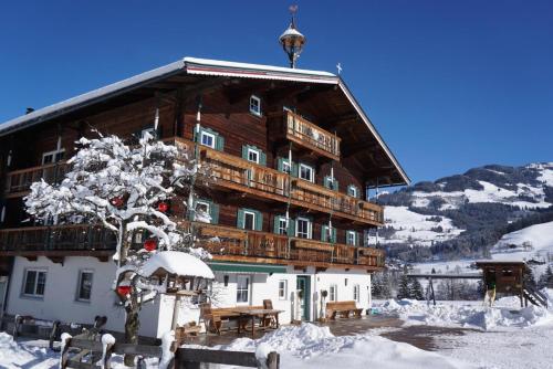 un grand bâtiment en bois avec de la neige au sol dans l'établissement Angererhof, à Jochberg