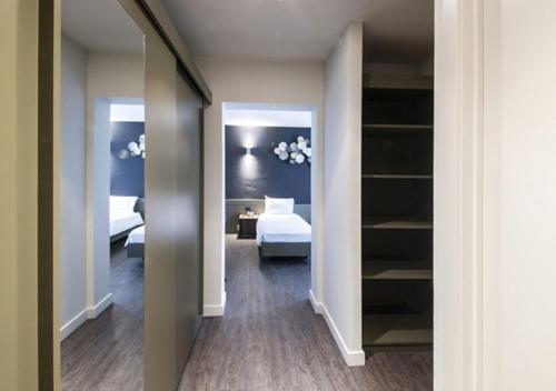 a hallway with a bedroom with a bed and a mirror at Hotel Cortina in Wevelgem
