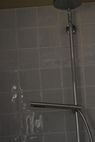 a shower with a tile wall and a shower head at Landhaus Schoener-Schalk in Longeville-sur-Mer