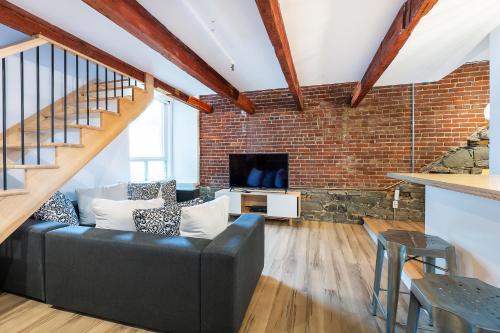 a living room with a black couch and a brick wall at Les Lofts St-Paul - Par Les Lofts Vieux-Québec in Quebec City