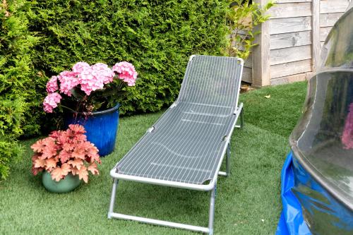 a metal bench sitting on the grass next to flowers at Celebration Wellnesshuisje in Balkbrug
