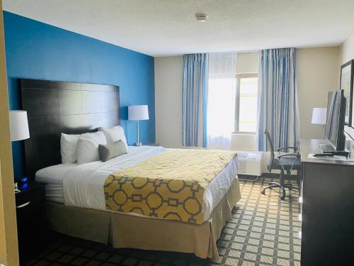 a hotel room with a large bed and a desk at Baymont by Wyndham Latham Albany Airport in Latham