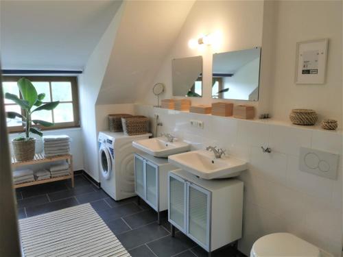 a bathroom with two sinks and a washing machine at Ferienwohnung mit Alpenblick in Antdorf