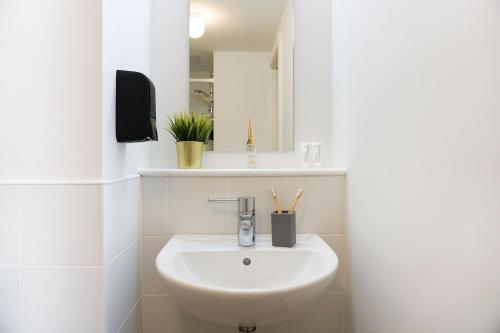 Baño blanco con lavabo y espejo en Swuite Dublin, en Dublín