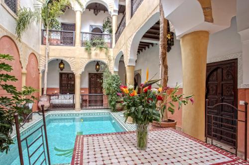an indoor pool in a building with a vase of flowers at Riad Itrane in Marrakesh