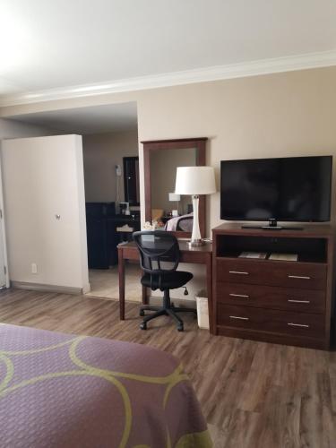 a hotel room with a bed and a desk with a television at Super 8 by Wyndham Los Angeles-Culver City Area in Los Angeles