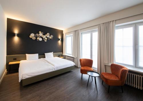 a hotel room with a bed and two chairs at Hotel Cortina in Wevelgem