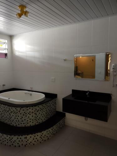 a bathroom with a tub and a sink and a mirror at Motel Paradise (Adults only) in São José dos Campos