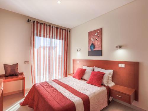 um quarto com uma cama com almofadas vermelhas e uma janela em V4, Villa Jardins Branqueira near Beach, Albufeira em Albufeira