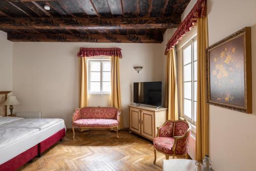 een slaapkamer met een bed en een tv en 2 stoelen bij Hotel Residence Green Lobster in Praag