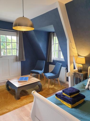 sala de estar con paredes azules, mesa y sillas en Chambre d’hôte Normande, en Freneuse-sur-Risle