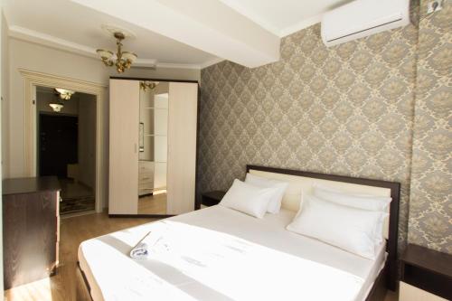 1 dormitorio con cama blanca y pared en Residential complex Central 271, en Almaty