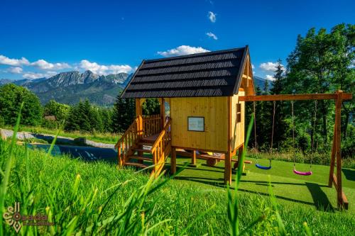 a small house with a playground in the grass at Osada Kościelisko - Tatry na Wyciągnięcie Ręki in Kościelisko