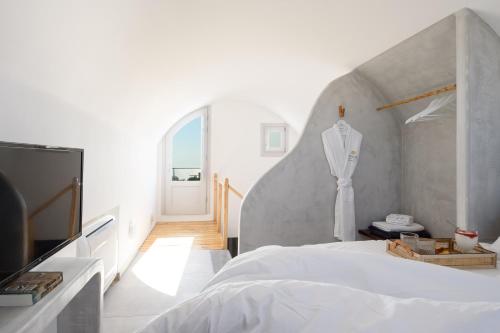 a white bedroom with a bed and a tv at Soil of Sun Luxury Villas in Megalochori