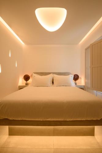 a bedroom with a large bed with a large light on the ceiling at Soil of Sun Luxury Villas in Megalokhori