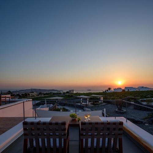 a balcony with a table and chairs and a sunset at Soil of Sun Luxury Villas in Megalokhori