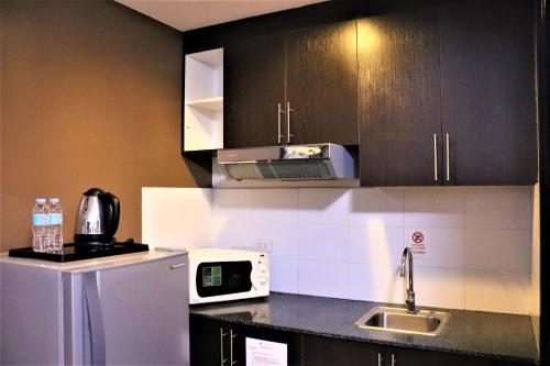 a kitchen with a microwave and a refrigerator at The Studio 18 Residences in Manila