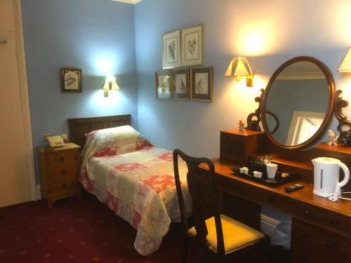a bedroom with a bed and a desk with a mirror at The Wynnstay in Machynlleth