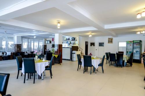 a dining room with tables and chairs and a kitchen at Pensiune Roata Cu Noroc in Sighetu Marmaţiei