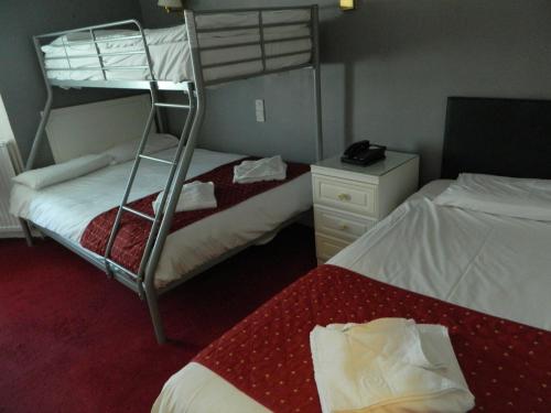 a bedroom with two beds and a bunk bed at Afton Hotel in Eastbourne