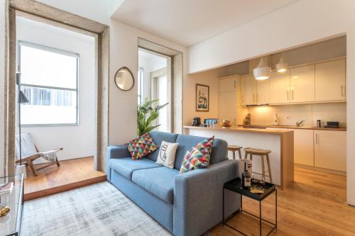 a living room with a blue couch and a kitchen at Apartamentos Villa Bolhao in Porto