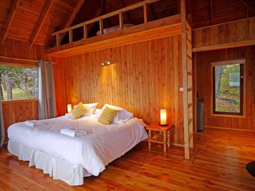 a bedroom with a bed in a room with wooden walls at Terra Luna Lodge in Puerto Guadal