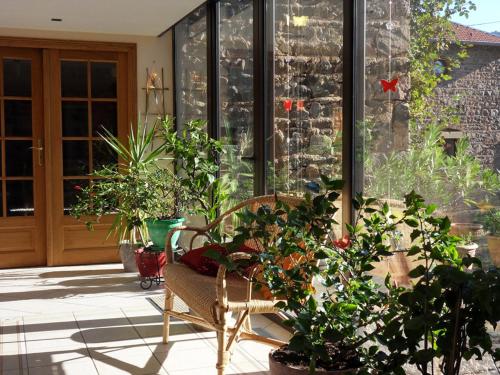 a porch with plants and a chair on a patio at Aux 3 sapins in Ronno