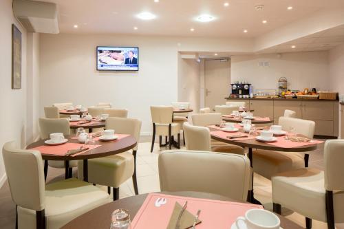 Un restaurante con mesas y sillas y una cocina. en Hôtel Ours Blanc - Wilson, en Toulouse