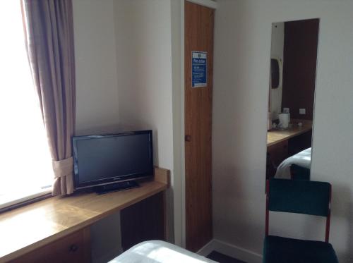 um quarto com uma televisão numa secretária com uma janela em The Premier Lodge em Morpeth
