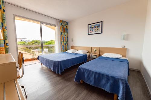 une chambre d'hôtel avec deux lits et une fenêtre dans l'établissement Hotel du Port, à Canet