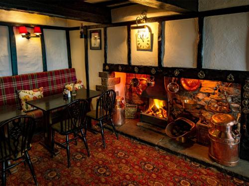 a restaurant with a fireplace and a table and chairs at The Barrel Inn in Eyam