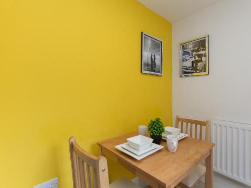 una sala da pranzo con tavolo in legno e pareti gialle di TownHouse @ West Avenue Crewe a Crewe