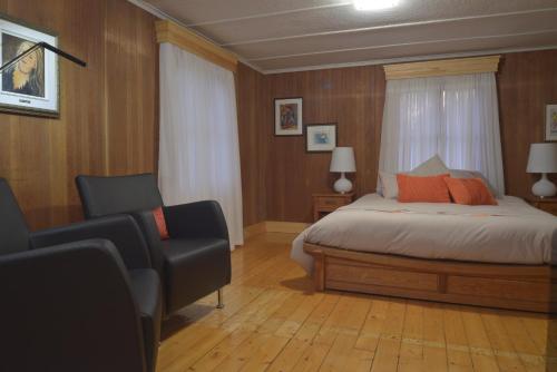 1 dormitorio con 1 cama, 2 sillas y ventana en Auberge À La Chouenne en La Malbaie