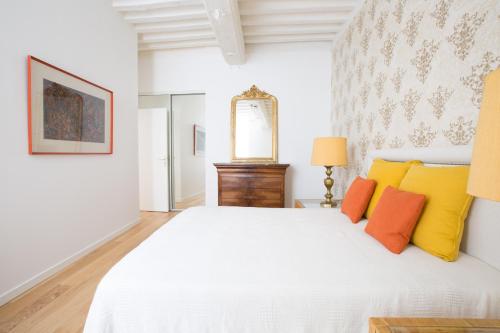 1 dormitorio con 1 cama blanca con almohadas de color naranja y amarillo en L'Aubertine en Beaune