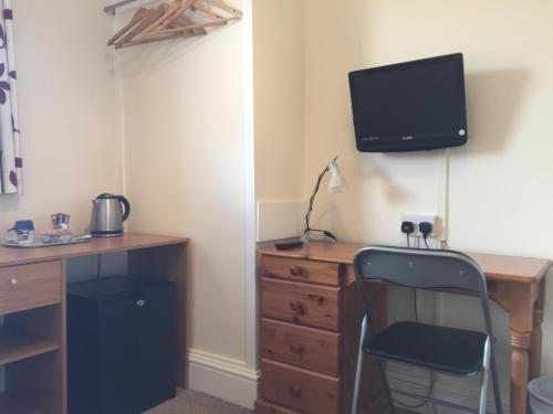 a desk with a chair and a tv on a wall at Barbican Reach Guest House in Plymouth