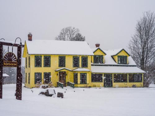 a yellow house with snow on top of it at Bark Eater Inn in Keene