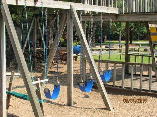 a playground with blue swings in a park at Bar M Resort & Campground in Branson West