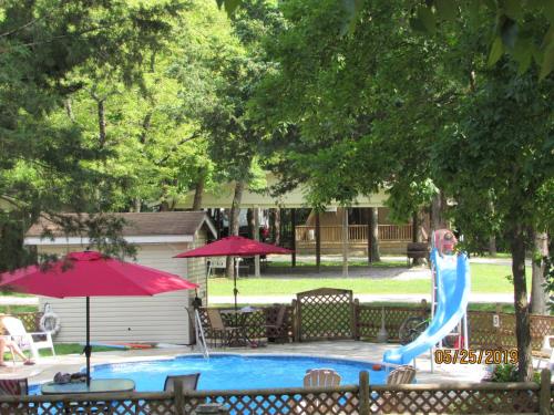 a blue water slide in a pool with chairs and umbrellas at Bar M Resort & Campground in Branson West