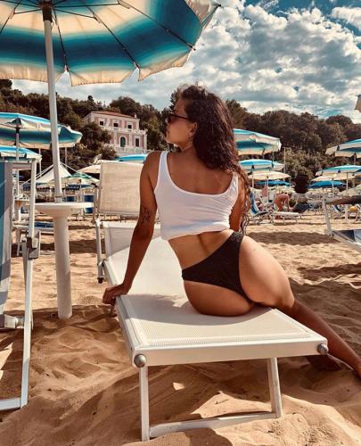 a woman in a bikini sitting on a chair on the beach at B&B Vista Mare in Rodi Garganico
