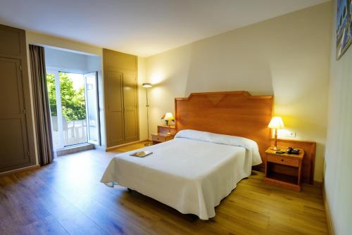 a bedroom with a white bed and a large window at Hotel Monarque El Rodeo in Marbella