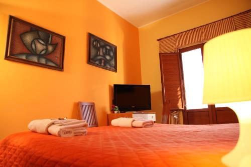 a bedroom with a bed with orange walls and a television at B&B Villa Casablanca in Enna