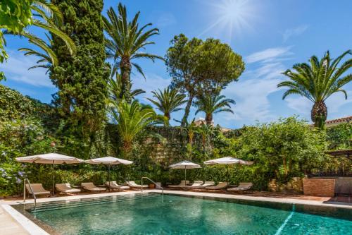 uma piscina com cadeiras e guarda-sóis e palmeiras em Boutique Hotel Las Islas em Fuengirola