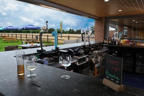 a bar with two wine glasses on a counter at The Queens At Horton in Telford