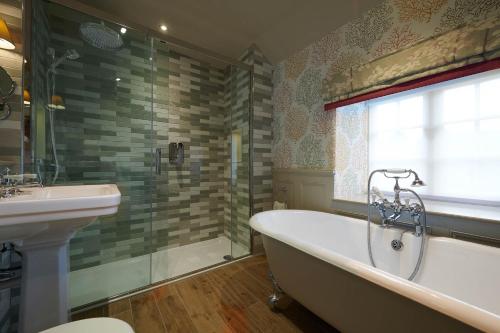 a bathroom with a bath tub and a sink at Cavendish Hotel in Baslow
