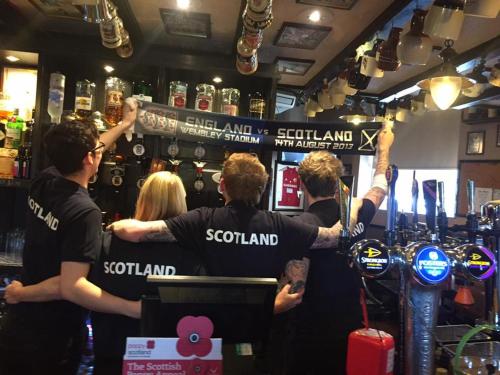 a group of people standing in a bar at The Blackbull Inn Polmont in Polmont